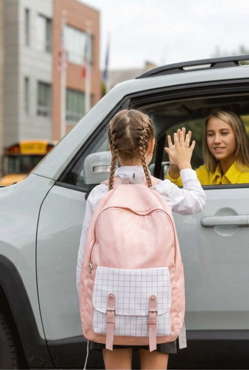 female driver and young girl saying goodbye at school drop off